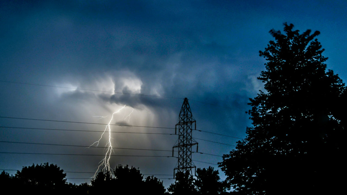 Rayo cayendo cerca de una torre de energía eléctrica de noche